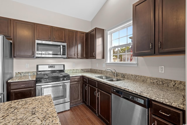 kitchen with light stone countertops, dark hardwood / wood-style flooring, stainless steel appliances, vaulted ceiling, and sink