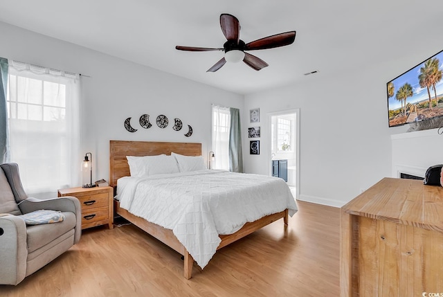 bedroom with ceiling fan, multiple windows, and light hardwood / wood-style flooring