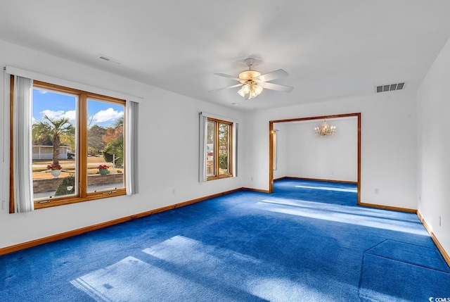 carpeted empty room featuring a healthy amount of sunlight and ceiling fan with notable chandelier