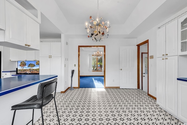 kitchen with decorative light fixtures, white cabinetry, a breakfast bar area, and an inviting chandelier