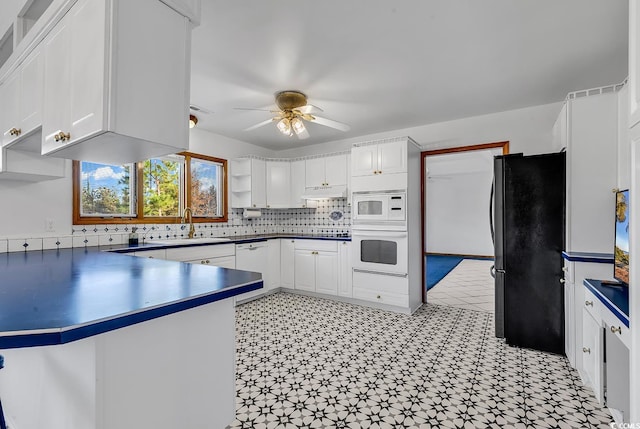 kitchen with white appliances, sink, kitchen peninsula, ceiling fan, and white cabinetry