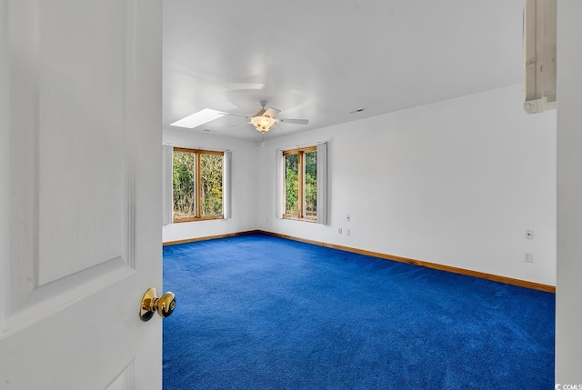 carpeted empty room with ceiling fan and a skylight