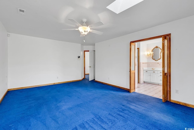 unfurnished bedroom featuring ceiling fan, ensuite bath, light colored carpet, and a skylight