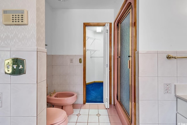 bathroom featuring vanity, a bidet, tile patterned floors, toilet, and tile walls