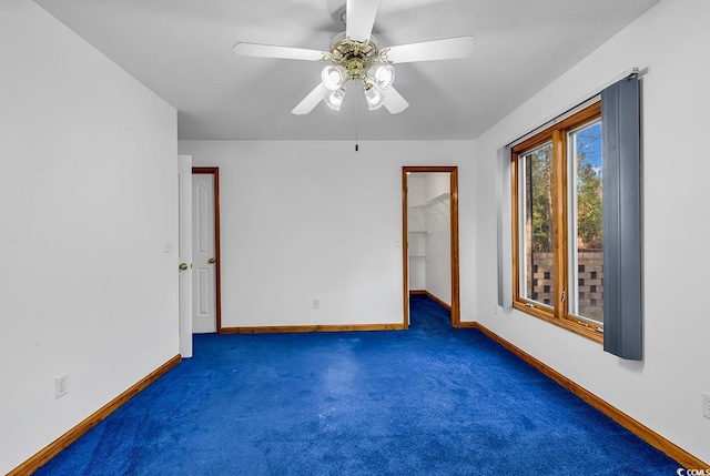 empty room with ceiling fan and dark colored carpet