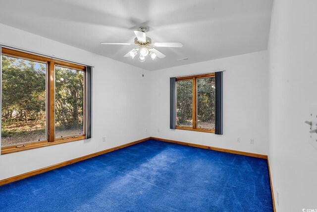 spare room featuring ceiling fan and dark colored carpet