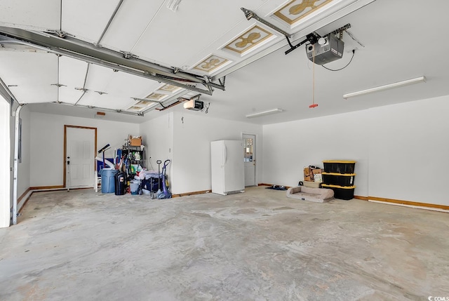 garage with a garage door opener and white refrigerator