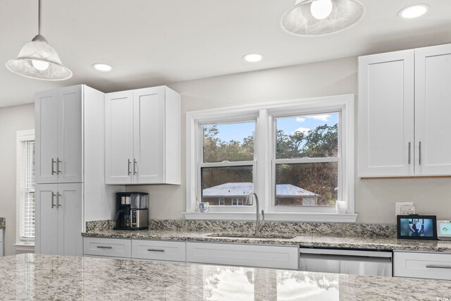 kitchen featuring sink, light stone counters, dishwasher, pendant lighting, and white cabinets