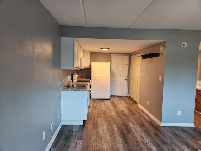 kitchen featuring white refrigerator, hardwood / wood-style flooring, white cabinetry, and sink