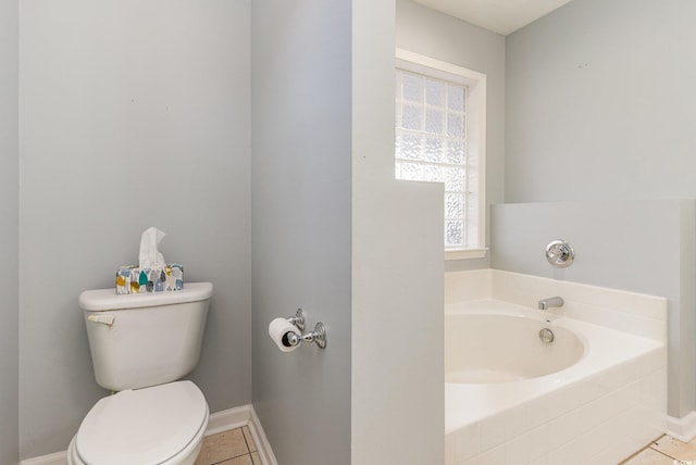 bathroom featuring tile patterned floors, a relaxing tiled tub, and toilet