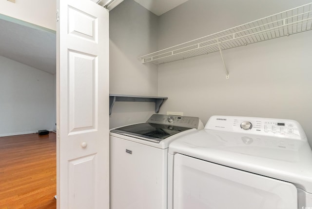 clothes washing area featuring washer and clothes dryer and wood-type flooring