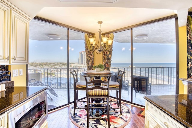 dining room with light hardwood / wood-style floors, floor to ceiling windows, a notable chandelier, and a water view