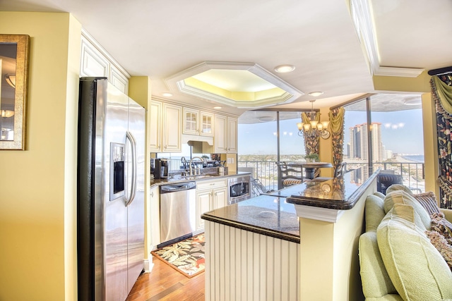 kitchen with hanging light fixtures, stainless steel appliances, light hardwood / wood-style flooring, a chandelier, and ornamental molding