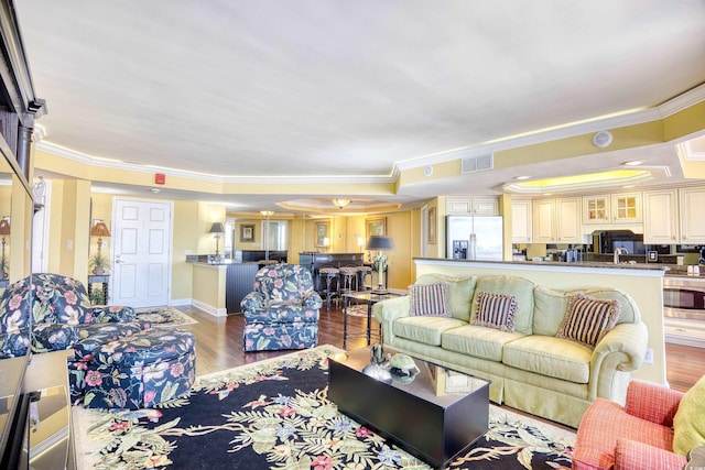 living room featuring light hardwood / wood-style floors, crown molding, and sink