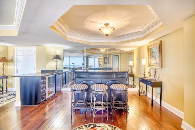 kitchen featuring dark hardwood / wood-style floors, a raised ceiling, blue cabinets, and a breakfast bar