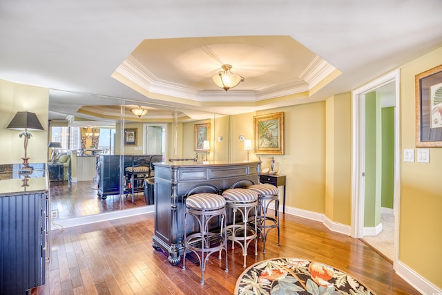 bar featuring hardwood / wood-style floors, a tray ceiling, and crown molding