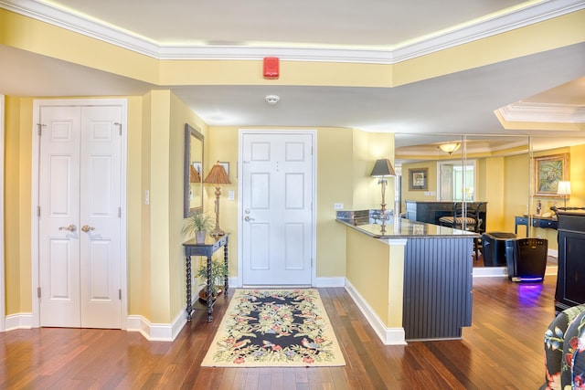 kitchen with kitchen peninsula, a breakfast bar, dark hardwood / wood-style floors, and ornamental molding