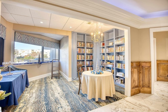 sitting room with built in shelves, crown molding, a drop ceiling, and a chandelier