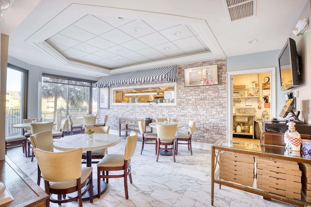 dining room featuring a raised ceiling and brick wall