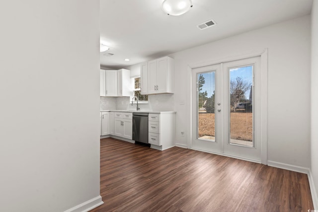 kitchen featuring white cabinets, stainless steel dishwasher, and a wealth of natural light