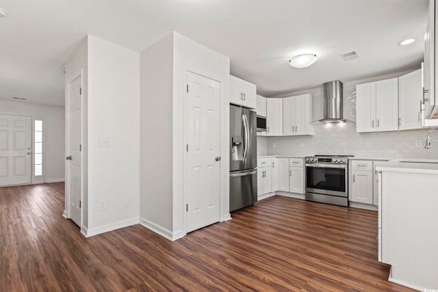 kitchen with white cabinetry, wall chimney range hood, dark wood-type flooring, and appliances with stainless steel finishes