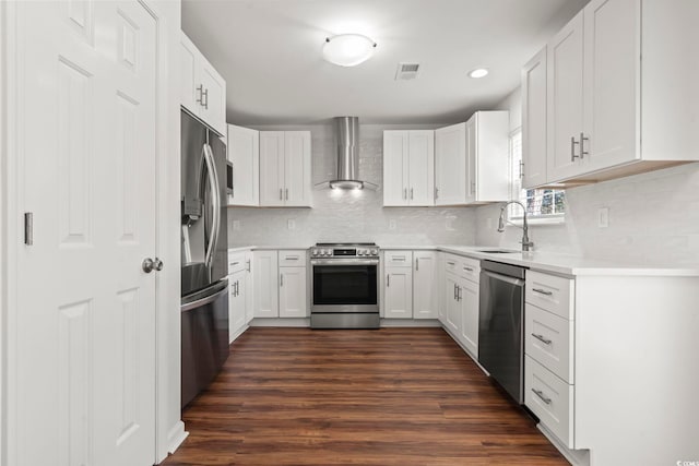 kitchen featuring appliances with stainless steel finishes, wall chimney exhaust hood, sink, white cabinets, and dark hardwood / wood-style floors