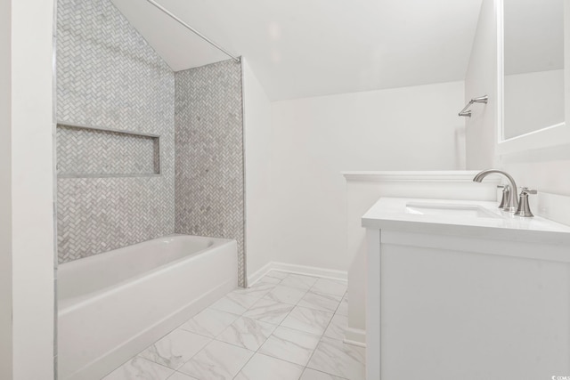 bathroom featuring vanity, tiled shower / bath, and vaulted ceiling