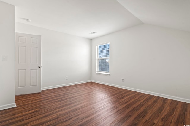 unfurnished room with vaulted ceiling and dark wood-type flooring