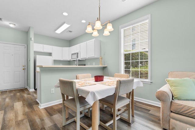 dining room with wood-type flooring and an inviting chandelier