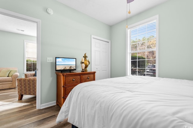 bedroom featuring a closet, light wood-type flooring, and multiple windows