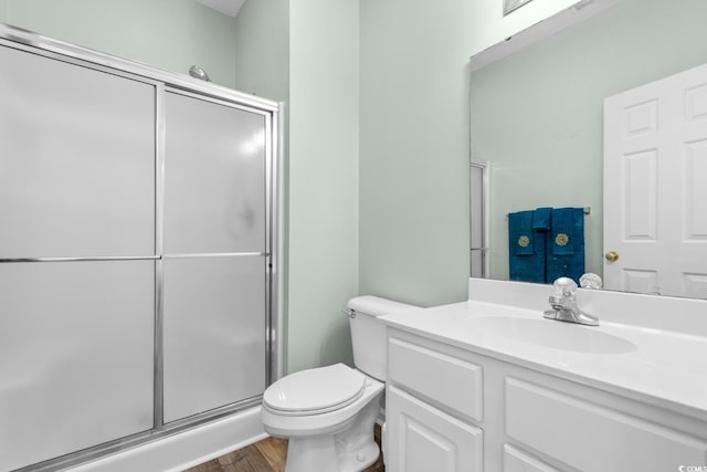 bathroom with hardwood / wood-style flooring, toilet, an enclosed shower, and vanity