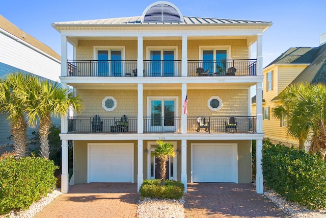 coastal home featuring a garage, a balcony, and french doors