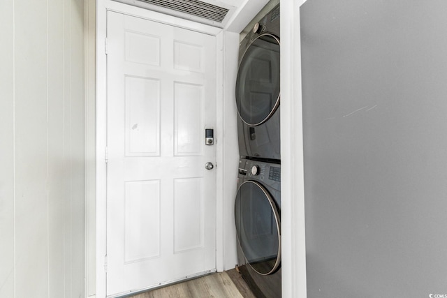 washroom with light hardwood / wood-style floors and stacked washer and dryer