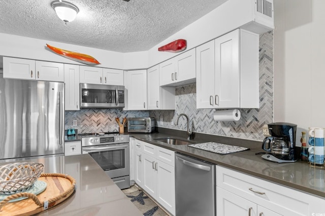 kitchen featuring decorative backsplash, appliances with stainless steel finishes, white cabinetry, and sink