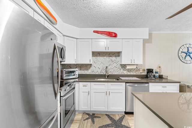 kitchen featuring white cabinetry, sink, wood walls, and appliances with stainless steel finishes