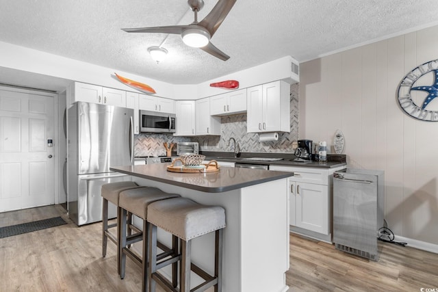 kitchen with a breakfast bar area, white cabinetry, light hardwood / wood-style flooring, and appliances with stainless steel finishes