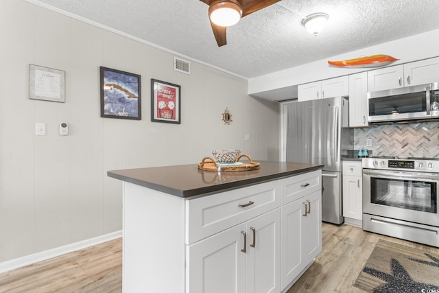 kitchen featuring decorative backsplash, white cabinetry, light wood-type flooring, and appliances with stainless steel finishes