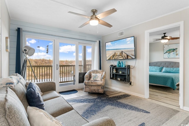 living room with light hardwood / wood-style floors, ceiling fan, and ornamental molding