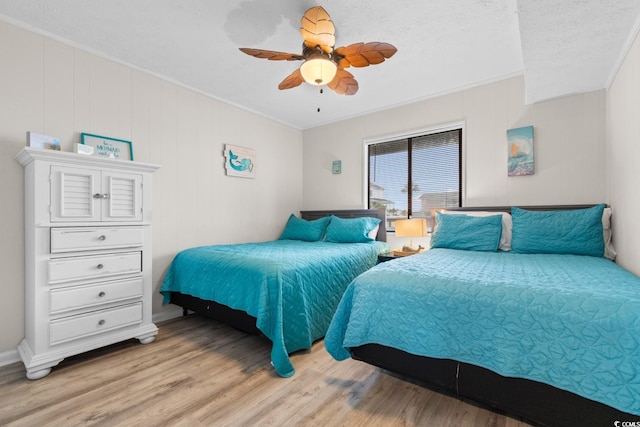 bedroom with ceiling fan, light hardwood / wood-style flooring, a textured ceiling, and ornamental molding