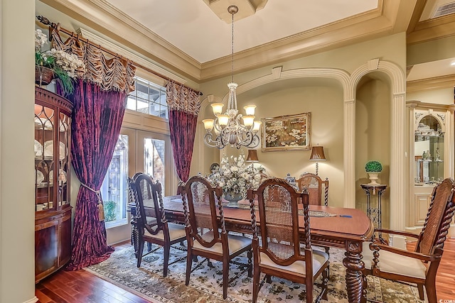 dining room with a chandelier, crown molding, wood-type flooring, and french doors