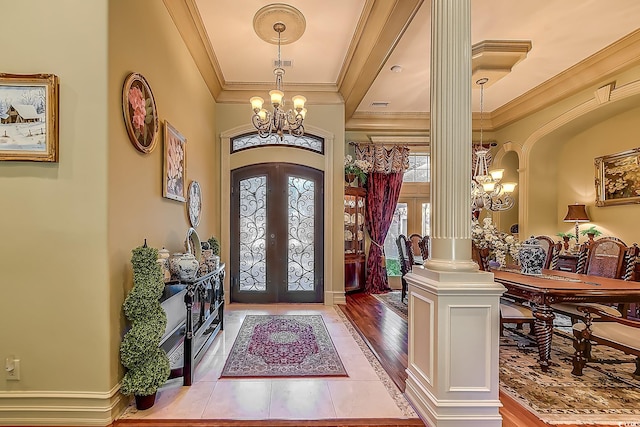 entryway featuring french doors, ornate columns, crown molding, hardwood / wood-style flooring, and a notable chandelier