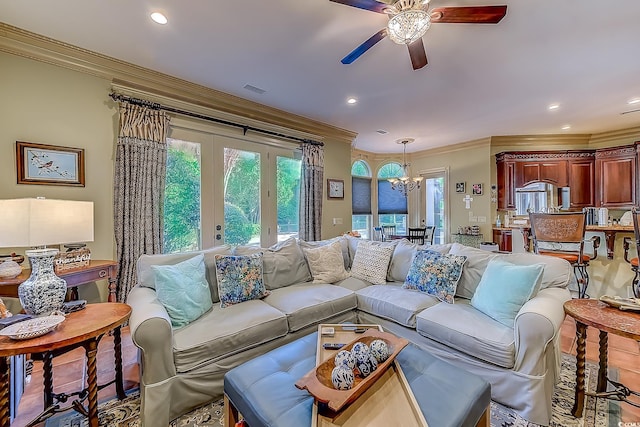 living room with hardwood / wood-style flooring, french doors, ceiling fan with notable chandelier, and ornamental molding