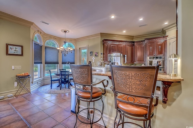 kitchen with decorative light fixtures, ornamental molding, a breakfast bar, and an inviting chandelier