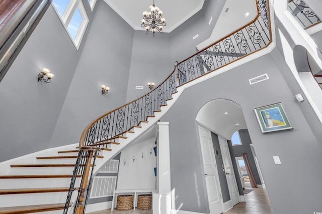 staircase featuring plenty of natural light, a towering ceiling, and a chandelier