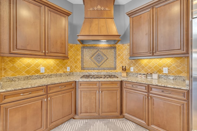 kitchen featuring backsplash, light stone countertops, and custom exhaust hood