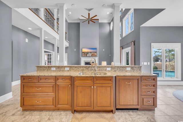 kitchen with light stone countertops, ornamental molding, sink, a high ceiling, and a center island