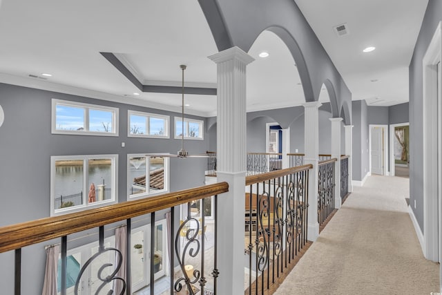 hallway with light colored carpet, ornate columns, and crown molding