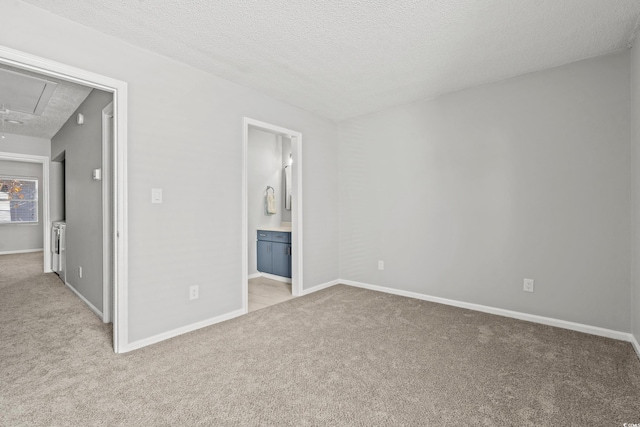 unfurnished bedroom featuring light carpet, connected bathroom, and a textured ceiling