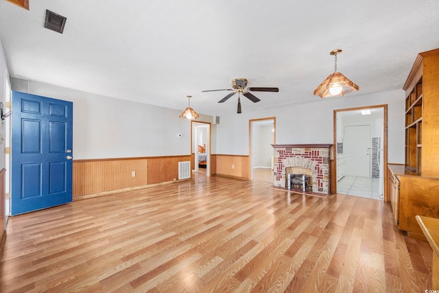 unfurnished living room featuring ceiling fan, light wood-type flooring, and a brick fireplace