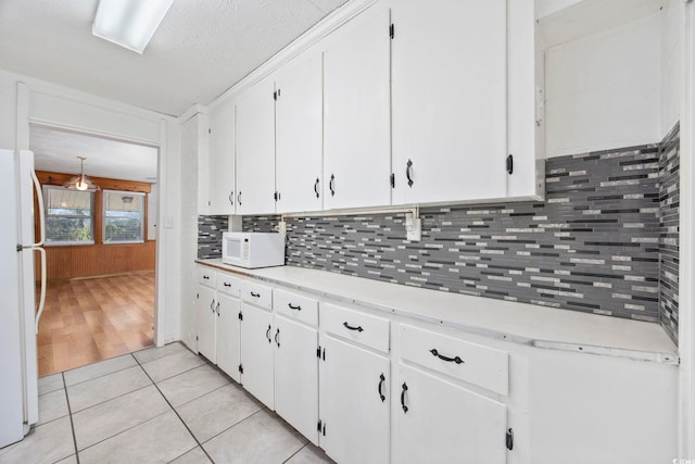 kitchen with tasteful backsplash, light tile patterned flooring, a textured ceiling, white appliances, and white cabinets